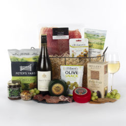 a basket with white wine, cheese, meat, crackers, and snacks