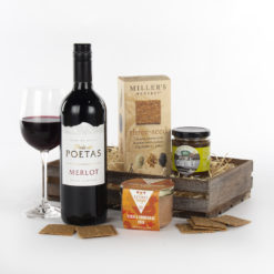 a wooden crate with a bottle of red wine, pate, chutney and crackers