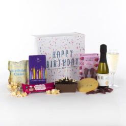 a happy birthday gift box with candle, champagne, and treats