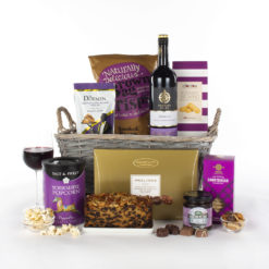 a gift basket with red wine, fruit cake, chocolates and other snacks