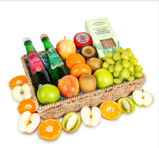 a basket with fruit, cheese, crackers, and two bottles of sparkling drink