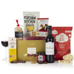 A mix of sweet and savory treats and snacks, and a bottle of red wine in a postal carton.