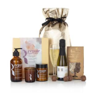 prosecco, chocolates, a candle, bath and body products in a gold bag
