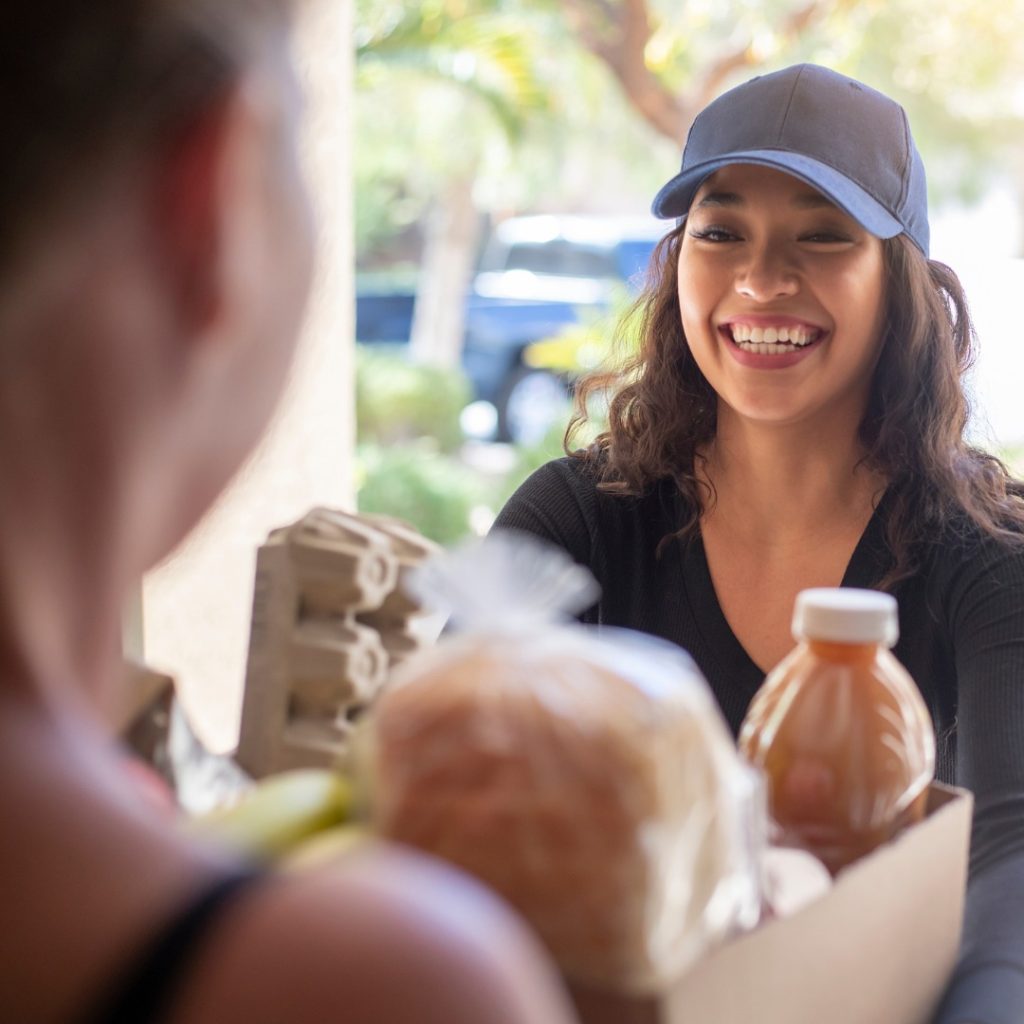 person delivery a box of food to someone's front dooer