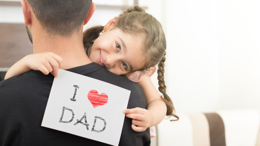 a little girl hugging her dad holding a sign that says I heart Dad