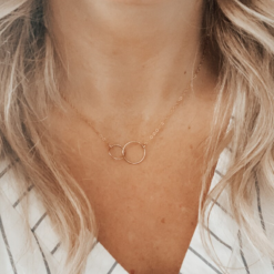 a gold necklace with two interlocking circles, one larger than the other
