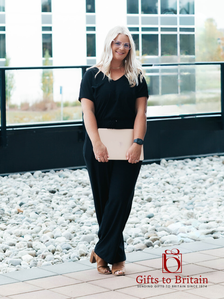 The owner of Gifts to Britain, Jess, standing on a balcony holding her laptop.